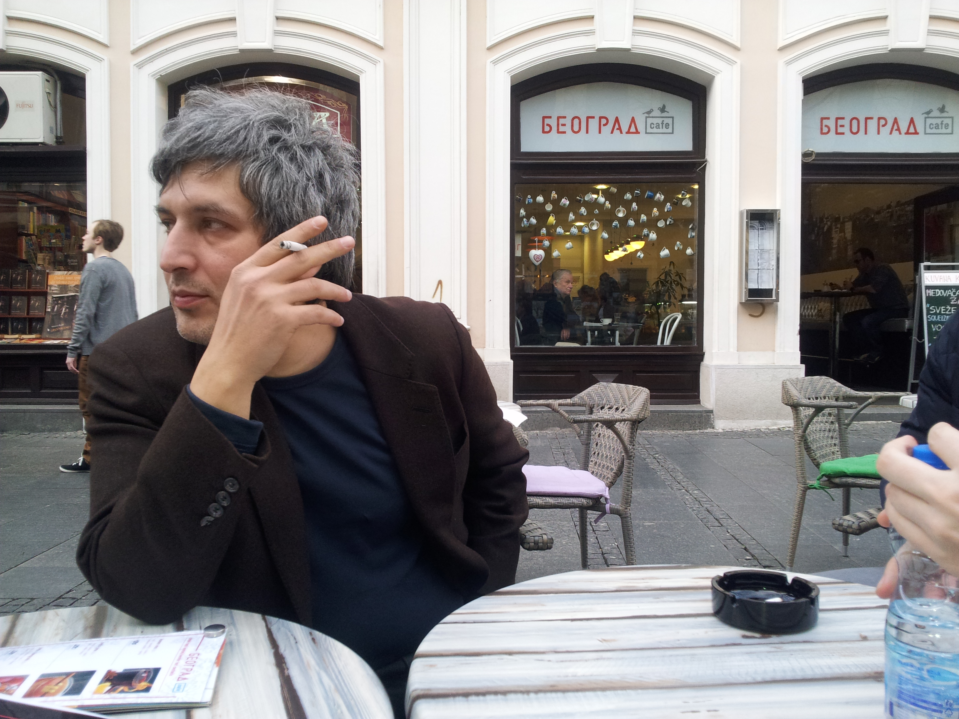 Semyon Khanin an einem Tisch sitzend, Zigarette rauchend